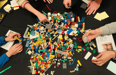 LEGO®ブロックを囲んでワークショップを進める参加者の手元。活発な対話と創造的な雰囲気が伝わる。