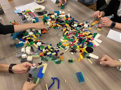 参加者がLEGO®ブロックで作品を制作している様子。テーブルに多様なパーツが広がり、活発な対話が行われている。